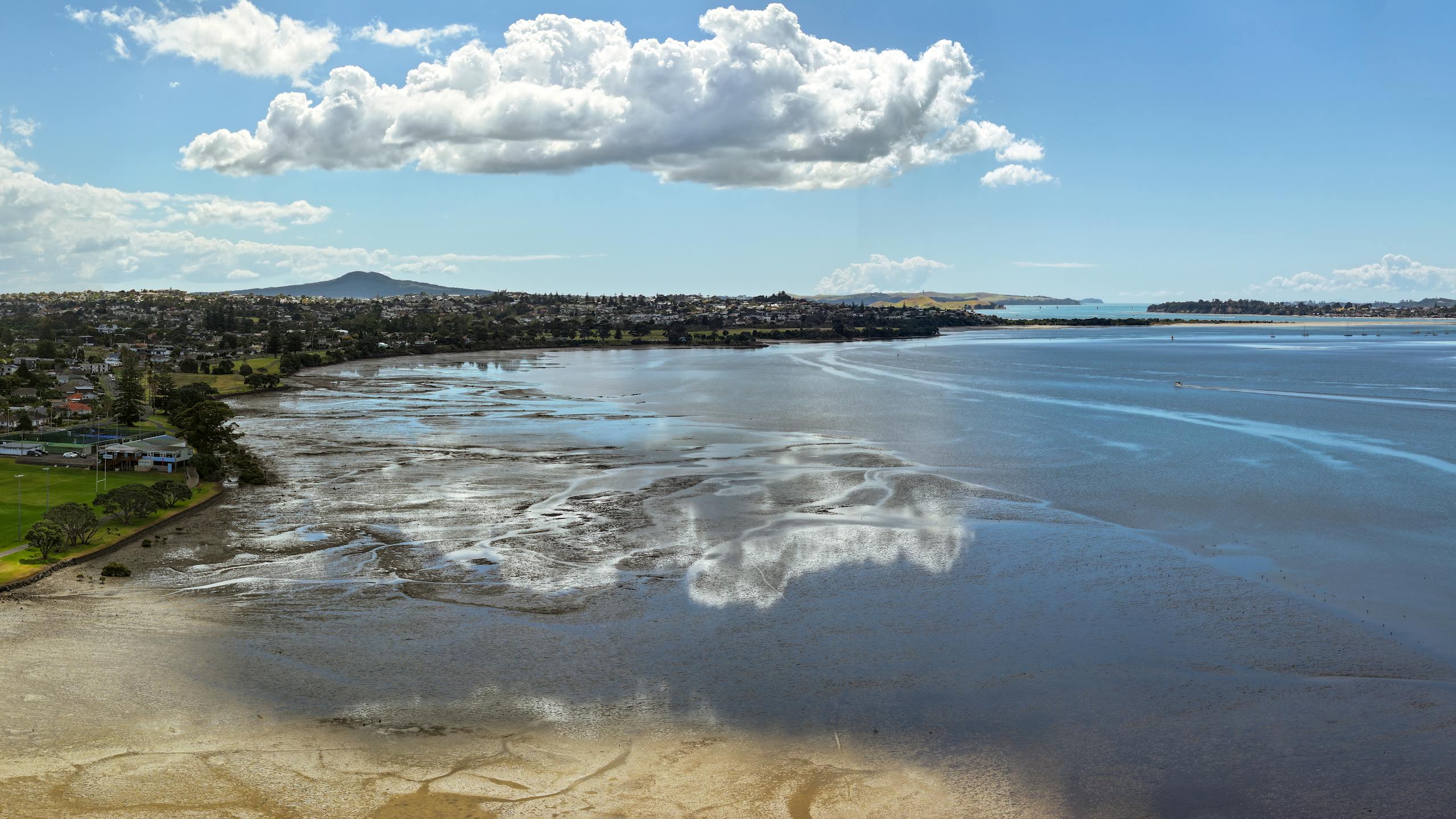 Explore Auckland's coastal beauty with a stunning aerial view of Rangitoto Island and calm waters reflecting the sky.