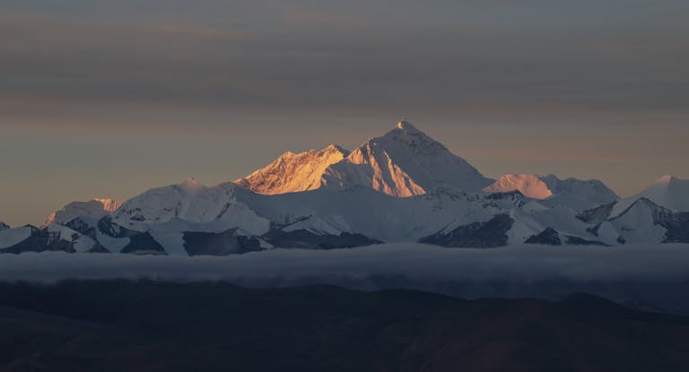 Stunning sunrise view of Mount Everest in the Himalayas with warm light on the snow-capped peaks.