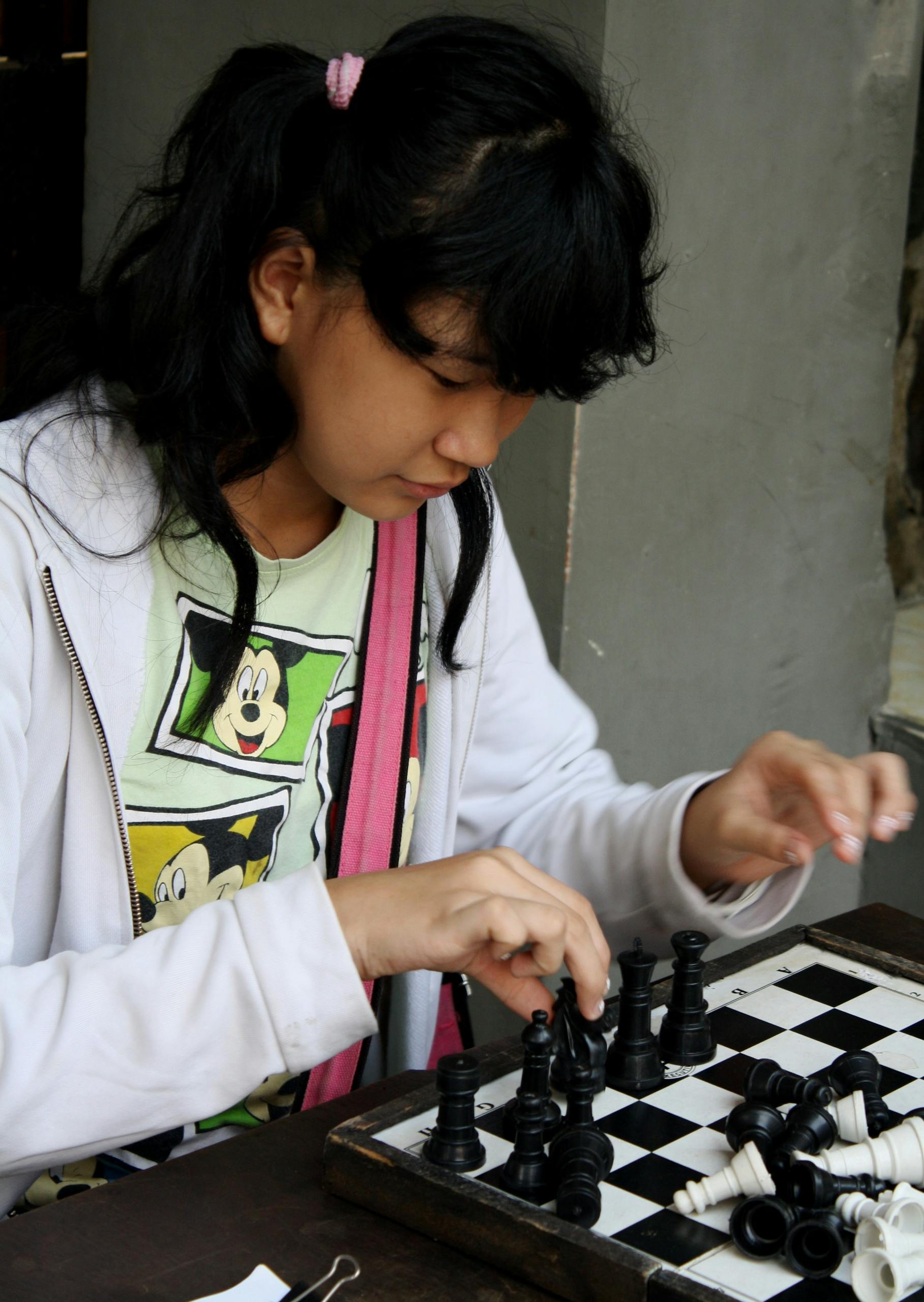 Young girl focusing on a chess game, emphasizing strategy and concentration.