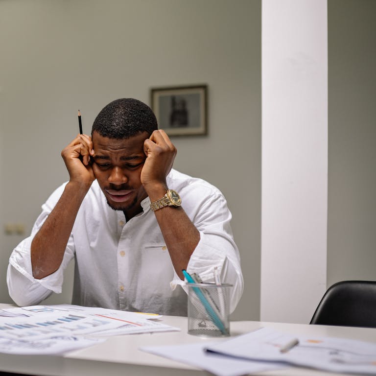 A worried businessman in corporate attire handling stress at his workspace.