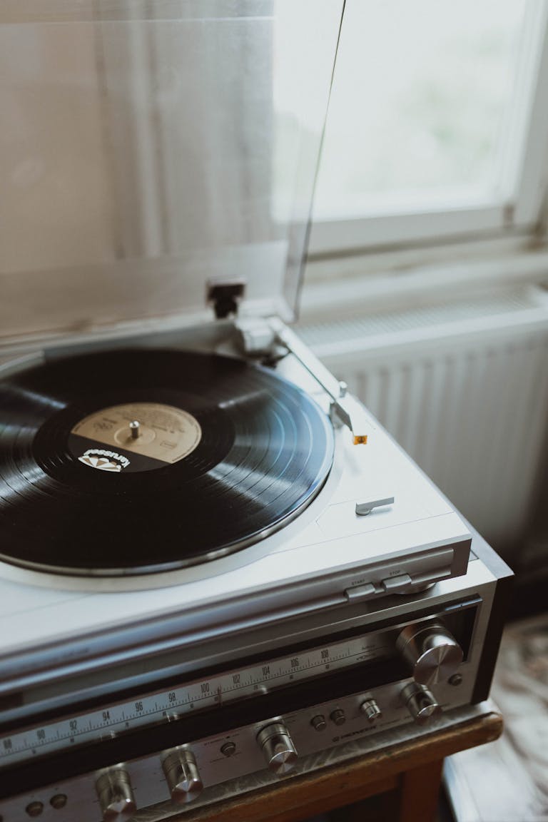Close-up of a vintage turntable spinning a vinyl record by a window.